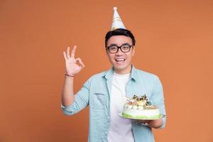 joven asiático sosteniendo pastel de cumpleaños foto