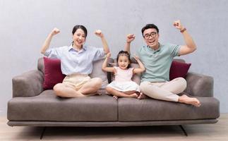 joven familia asiática sentada en el sofá foto