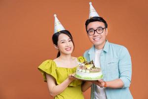 Young Asian couple holding birthday cake on background photo