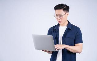 Young Asian man using laptop on white background photo