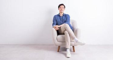 Young Asian man sitting on armchair on white background photo