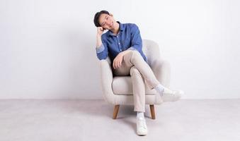 Young Asian man sitting on armchair on white background photo