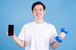 Young Asian man holding dumbbell on background photo