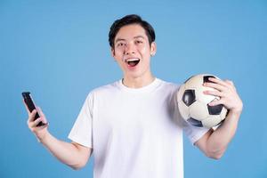 joven asiático sosteniendo la pelota en el fondo foto