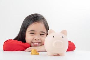 niña asiática ahorrando dinero en una alcancía, aprendiendo a ahorrar, los niños ahorran dinero para la educación futura. concepto de dinero, finanzas, seguros y personas foto