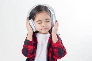 pequeña niña asia linda disfrutando de sus auriculares de música foto