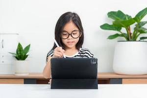 Asian child girl student wow excited on video call learning to studying online class or person learn from home school with tablet photo