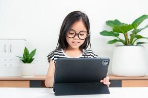 Asian child girl student wow excited on video call learning to studying online class or person learn from home school with tablet photo