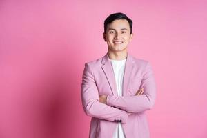 Portrait of young Asian man wearing pink suit posing on background photo