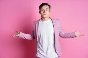 Portrait of young Asian man wearing pink suit posing on background photo