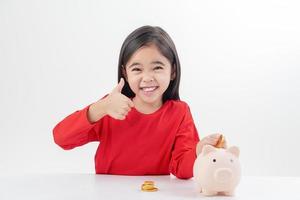 Little Asian girl saving money in a piggy bank, learning about saving, Kid save money for future education. Money, finances, insurance, and people concept photo