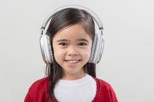 pequeña niña asia linda disfrutando de sus auriculares de música foto