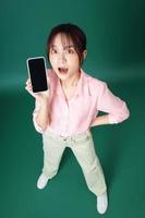 foto completa de una joven asiática usando un teléfono inteligente con fondo verde