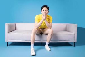 Image of young Asian man sitting on sofa photo