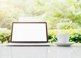 Laptop computer and cup of coffee on the table in morning photo