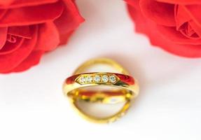 Red roses and gold rings on white photo