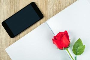 Red roses on blank notebook with smartphone Valentine concept photo