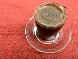 una taza de café negro en la alfombra roja foto