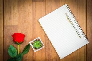 rosas rojas en la mesa de madera y el bloc de notas foto