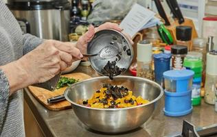 el chef cambia las aceitunas a la ensalada con calabacines, naranjas y salami. cocina gourmet francesa, sobre fondo de madera foto