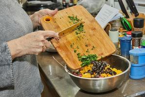 el chef convierte las verduras en una ensalada con calabacines, naranjas y salami. cocina gourmet francesa, sobre un fondo de madera
