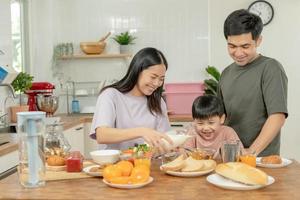 actividades juntos durante las vacaciones. padres e hijos están comiendo juntos durante las vacaciones. el niño se burla de su padre dándole pan y verduras. foto