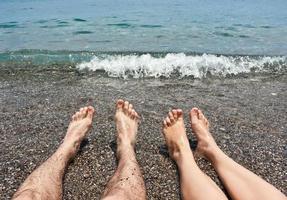 par de piernas en la playa del mar foto
