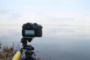 cámara de fotos en un trípode captura un hermoso paisaje marino, concepto de videografía