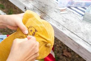 mano femenina sosteniendo un sombrero de bordado amarillo y una aguja trabajando en la costura de un patrón de gato en un proceso de trabajo manual. disfrutar del tiempo libre los fines de semana. foto