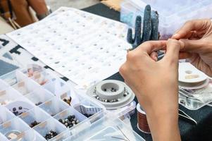 Close-up of a woman's hands stringing beads on the thread, making jewelry in the workshop. photo