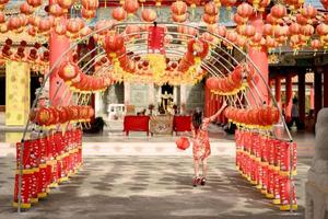 hermosa joven asiática con un vestido tradicional cheongsam qipao sosteniendo una linterna y caminando con la espalda mientras visitaba el templo budista chino. celebrar el año nuevo lunar chino. foto