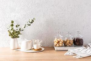 Beautiful kitchen background with items and products for the tea ceremony. glass jars with tea, sugar, biscuits and a white teapot and cups. photo