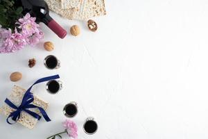 festive background of the Jewish Passover. four silver glasses with red wine, matzah, a bottle of wine, nuts. white textured background. a copy space. photo