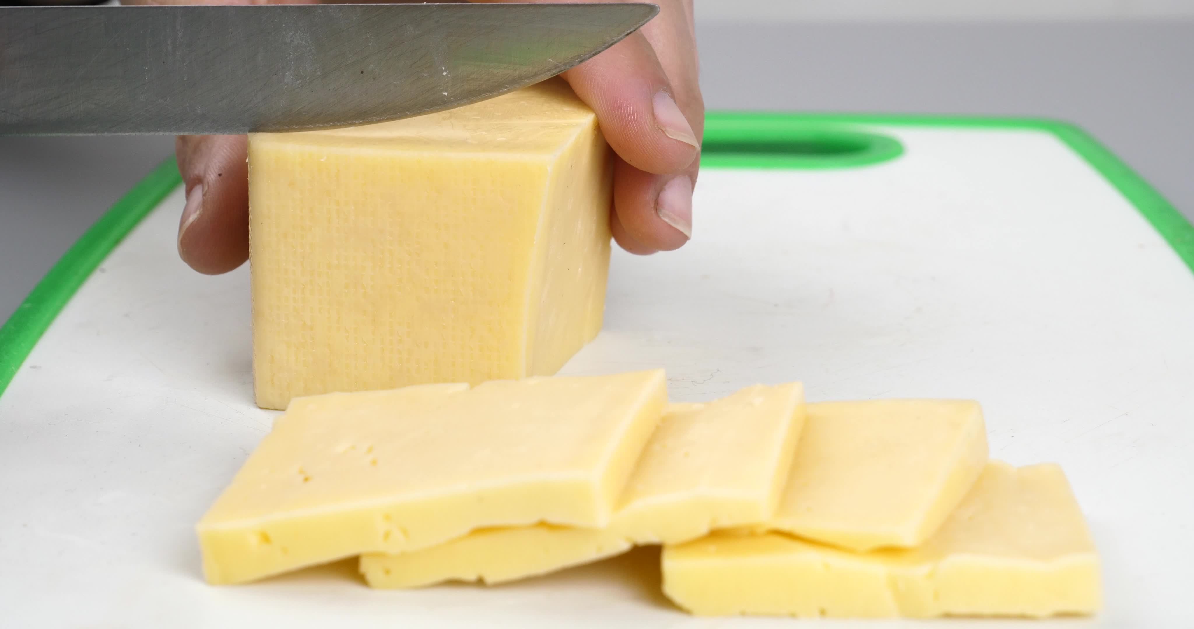cutting cheese into slice pieces with a knife closeup 17567276 Stock