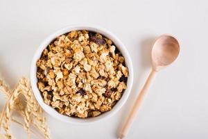 Baked granola in a bowl, wooden spoon and ears on the table. Healthy breakfast. Top view. photo