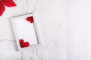 Blank photo frame and DIY paper hearts and leaves on plaster. Home decor. Copy space