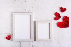 Paper red do-it-yourself hearts around empty photo frames on a concrete background. Valentine's Day.