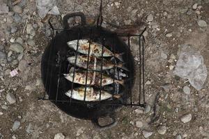 the process of making grilled fish that is burned over coconut shell coals photo