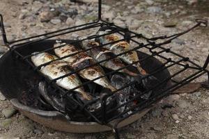 el proceso de hacer pescado a la parrilla que se quema sobre carbones de cáscara de coco foto