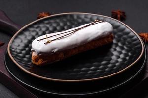 Deliciosos beneficios frescos o eclair con chocolate en un plato de cerámica negra. foto