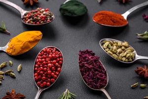 Variation of spices in metal spoons paprika, turmeric, cardamom, a mixture of allspice, thyme and rosemary photo