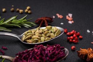 Variation of spices in metal spoons paprika, turmeric, cardamom, a mixture of allspice, thyme and rosemary photo