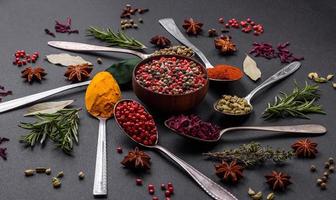 Variation of spices in metal spoons paprika, turmeric, cardamom, a mixture of allspice, thyme and rosemary photo