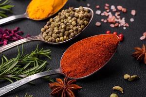 Variation of spices in metal spoons paprika, turmeric, cardamom, a mixture of allspice, thyme and rosemary photo