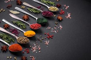 Variation of spices in metal spoons paprika, turmeric, cardamom, a mixture of allspice, thyme and rosemary photo