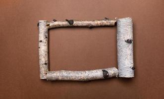 Bright natural brown background with frame of birch trunk parts and copy space for text inside it. photo