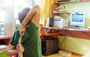 hombre maduro haciendo yoga remotamente en línea antes de la computadora en una habitación soleada en casa. estilo de vida saludable durante la pandemia. foto