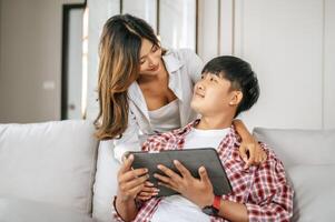 Young Asian couple enjoy with tablet together in living room photo