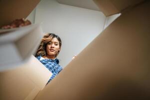 Young woman opening parcel pick up book out of box photo