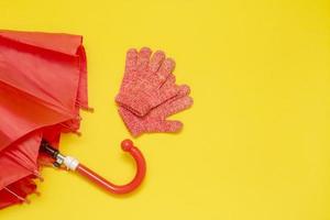 red children's umbrella and gloves on a yellow background with copy space photo